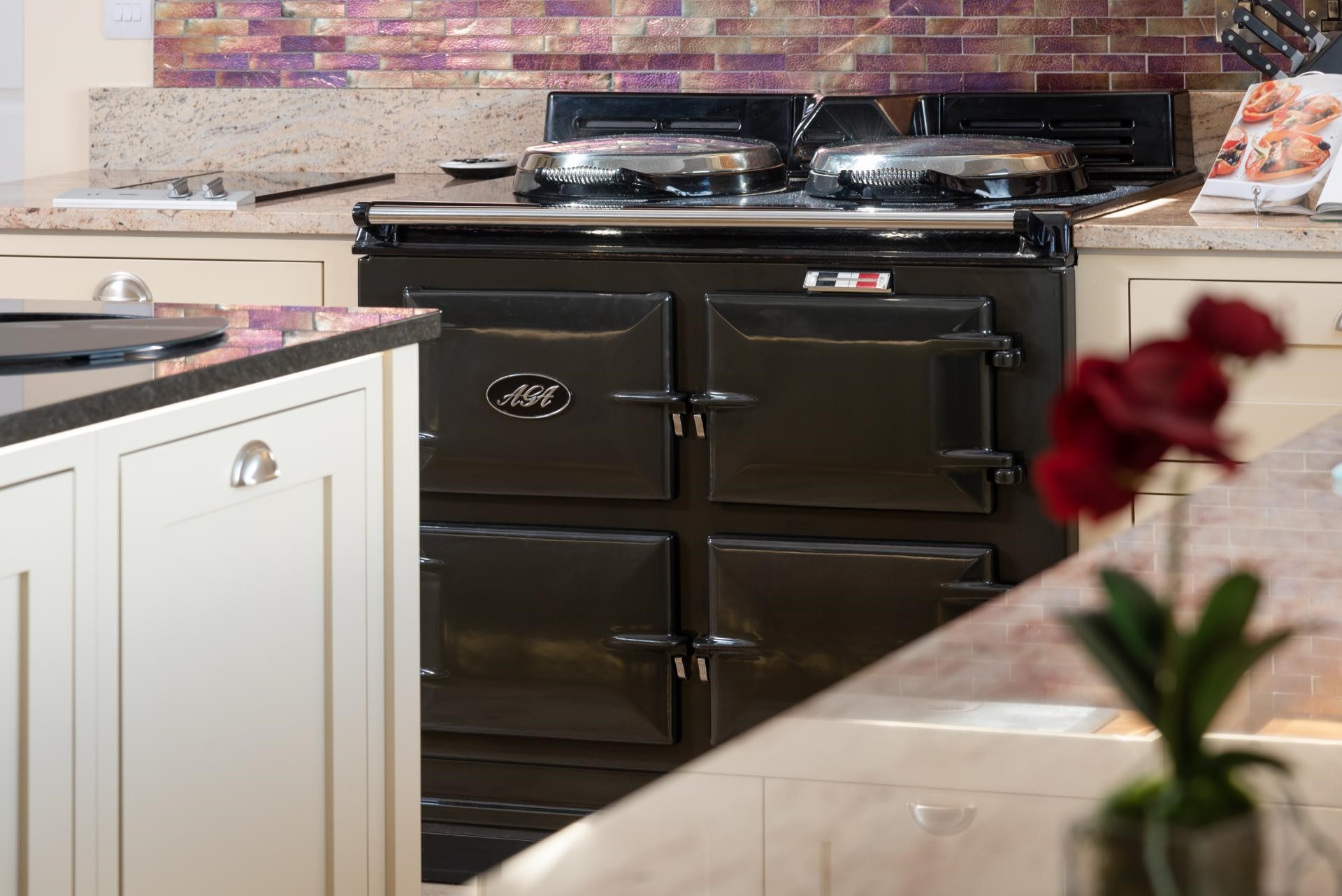 black four door AGA cooker with shimmery purple tile splashback in traditional shaker kitchen