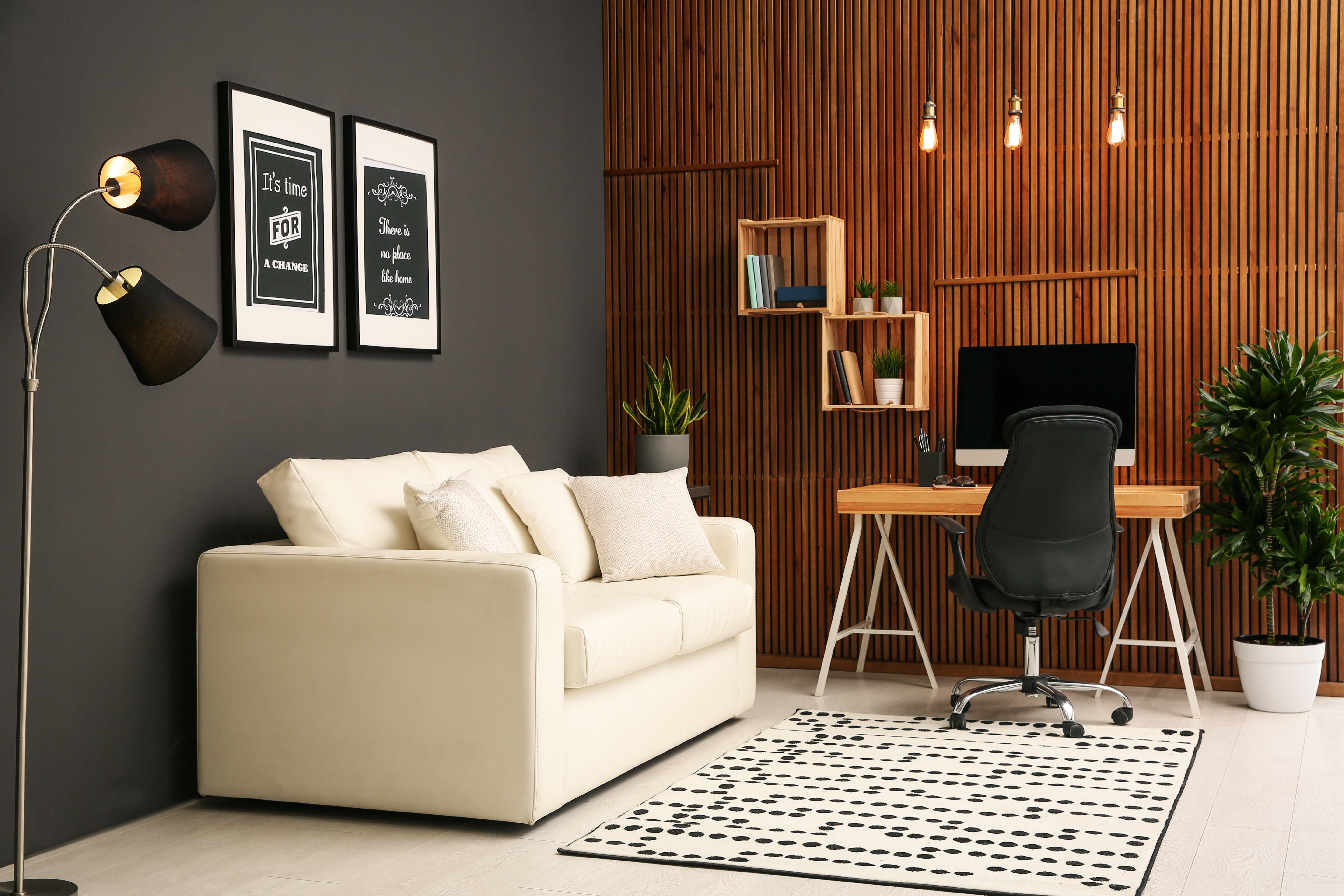 Comfortable workplace with computer near wooden wall in stylish room interior