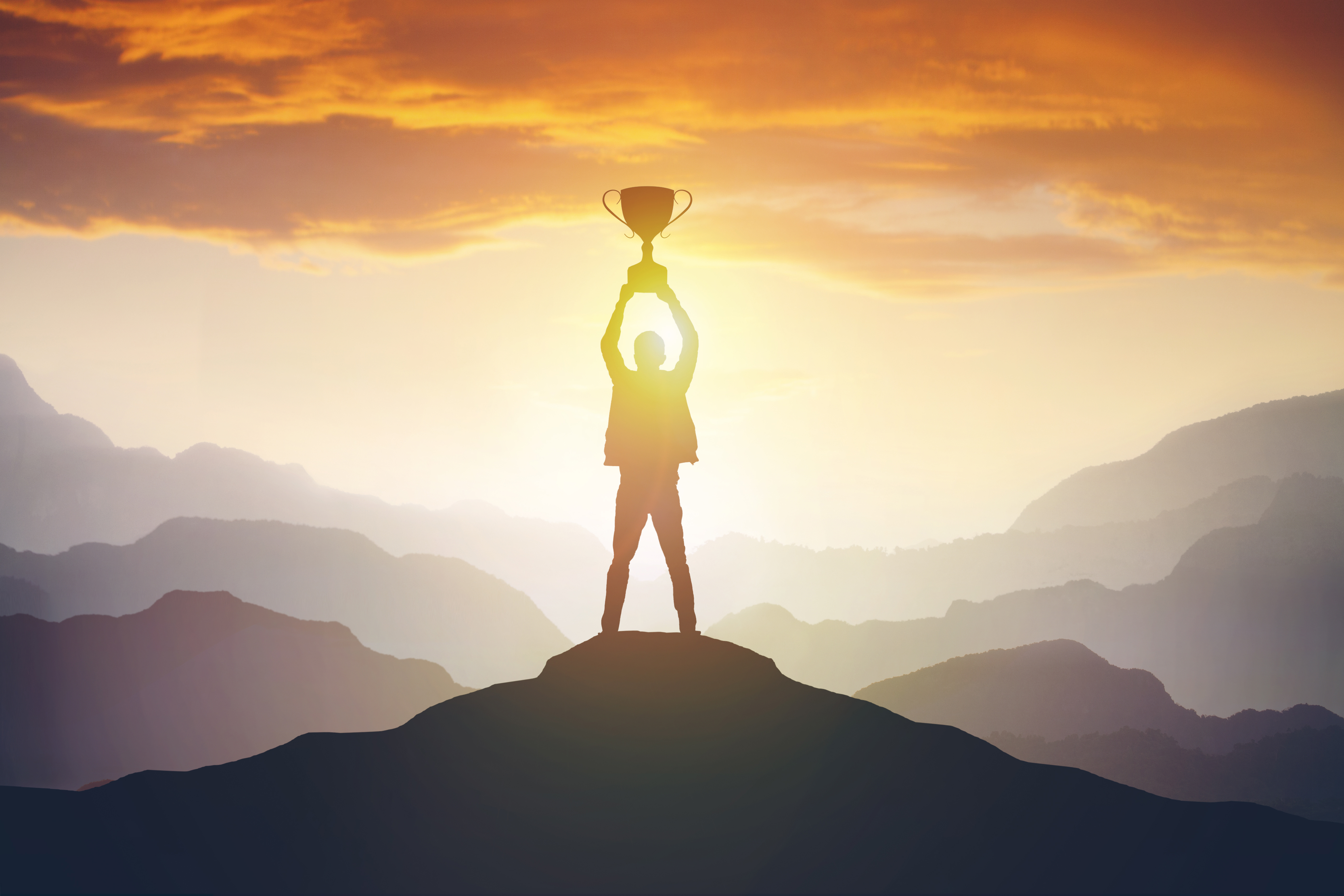 silhouette_of_a_man_holding_a_trophy_at_sunset