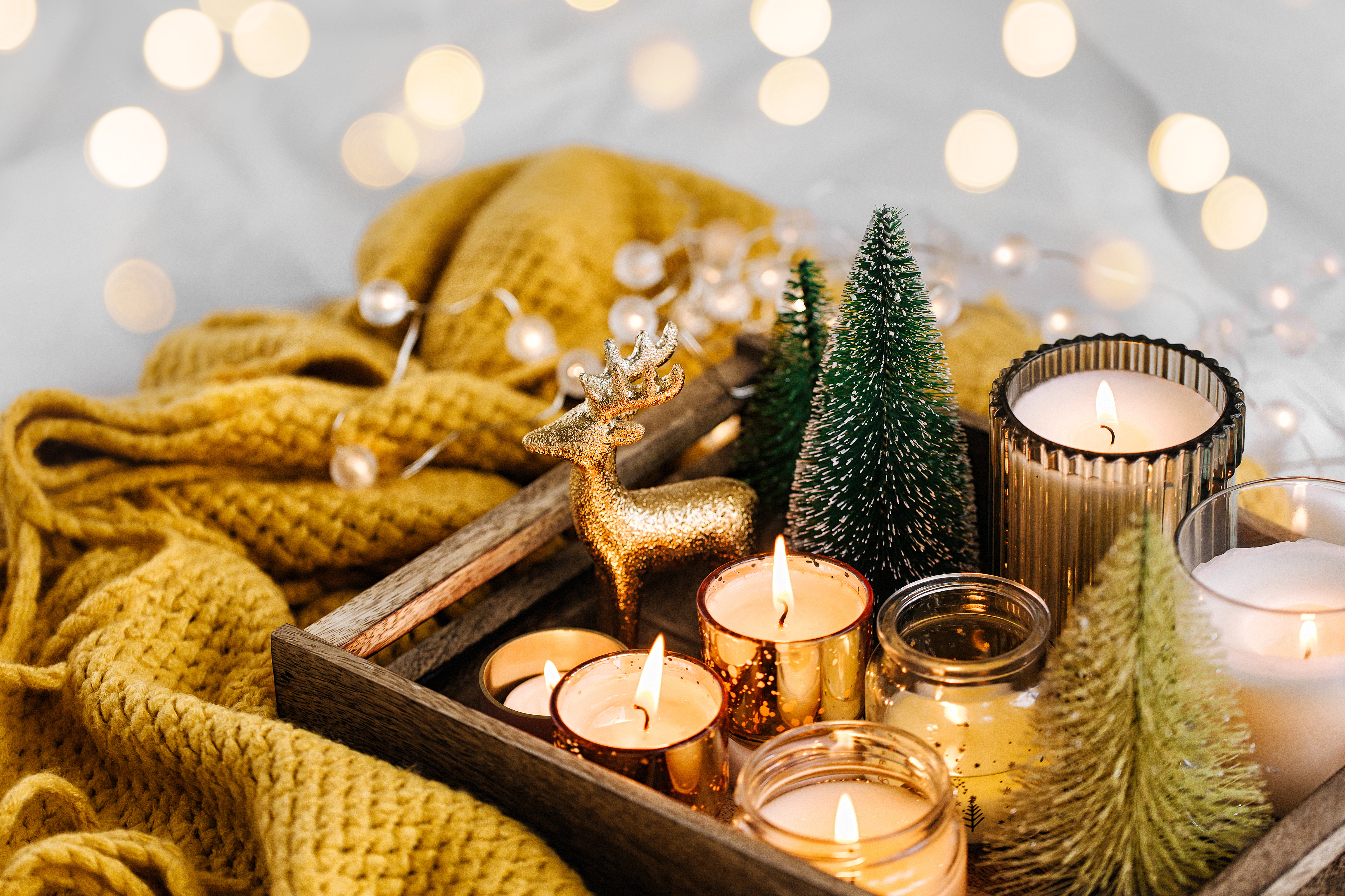 Burning candles and christmas decorations on wooden tray with warm plaid