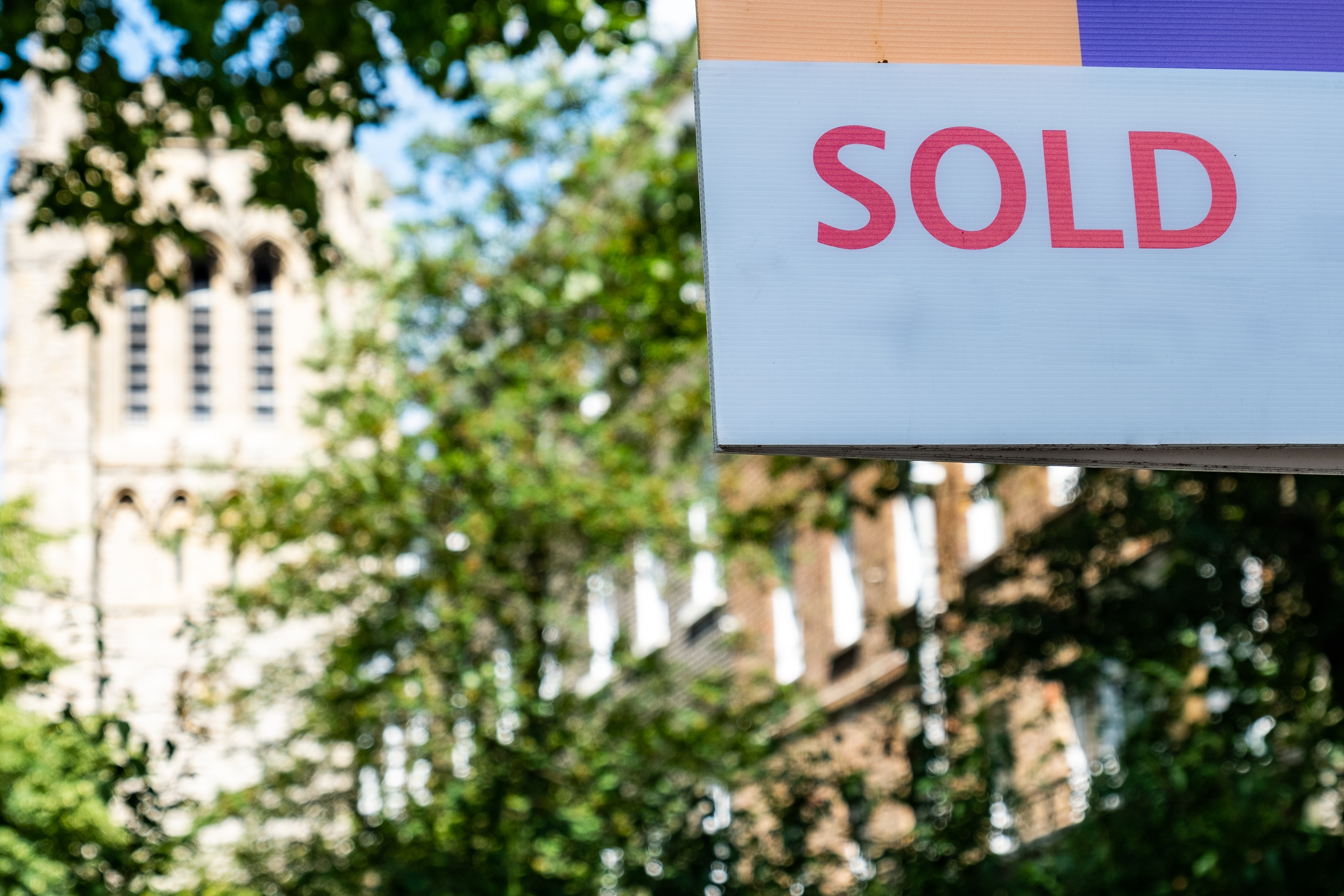 Estate agent 'SOLD' sign on street of urban houses