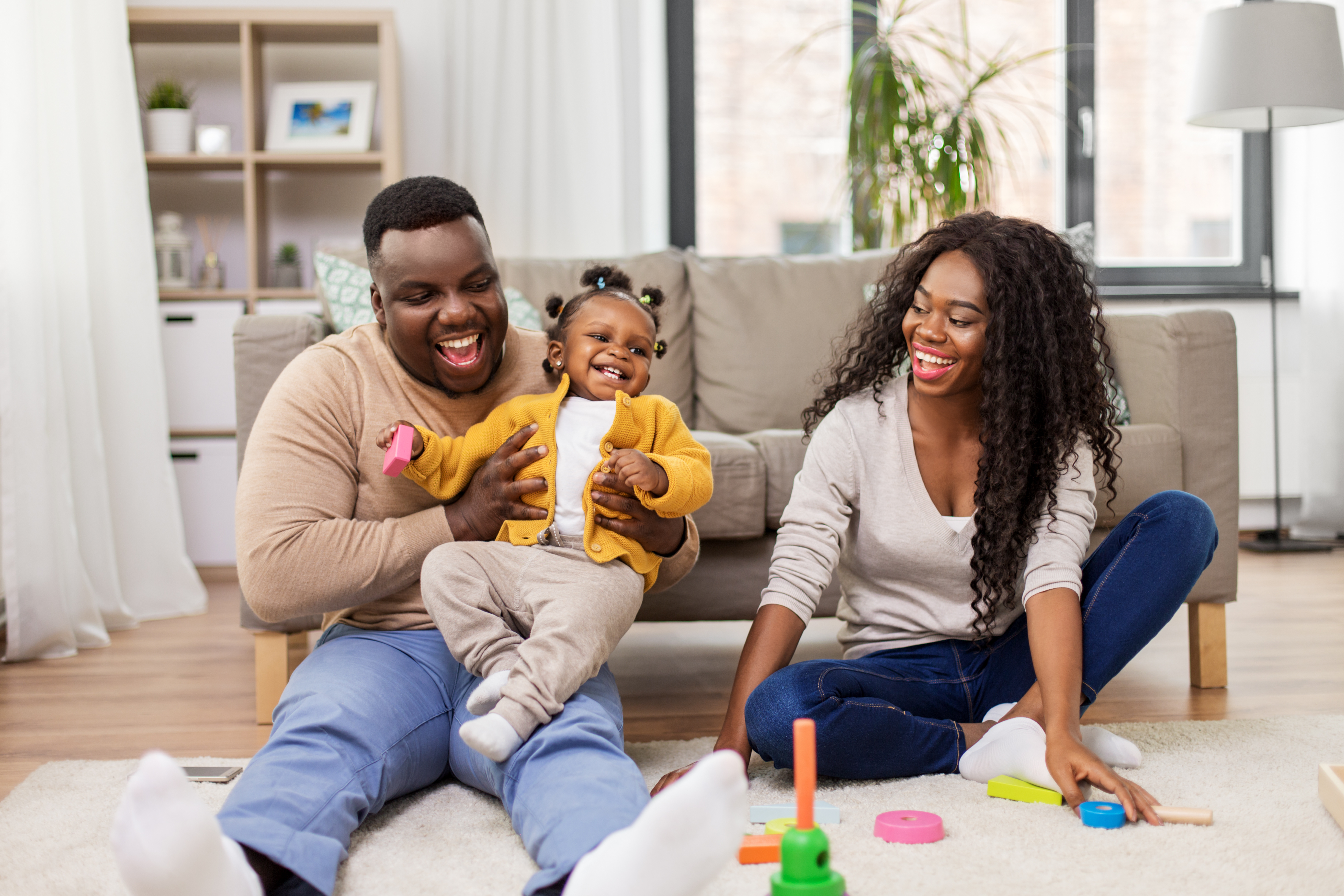 father and baby daughter playing with toy blocks at home