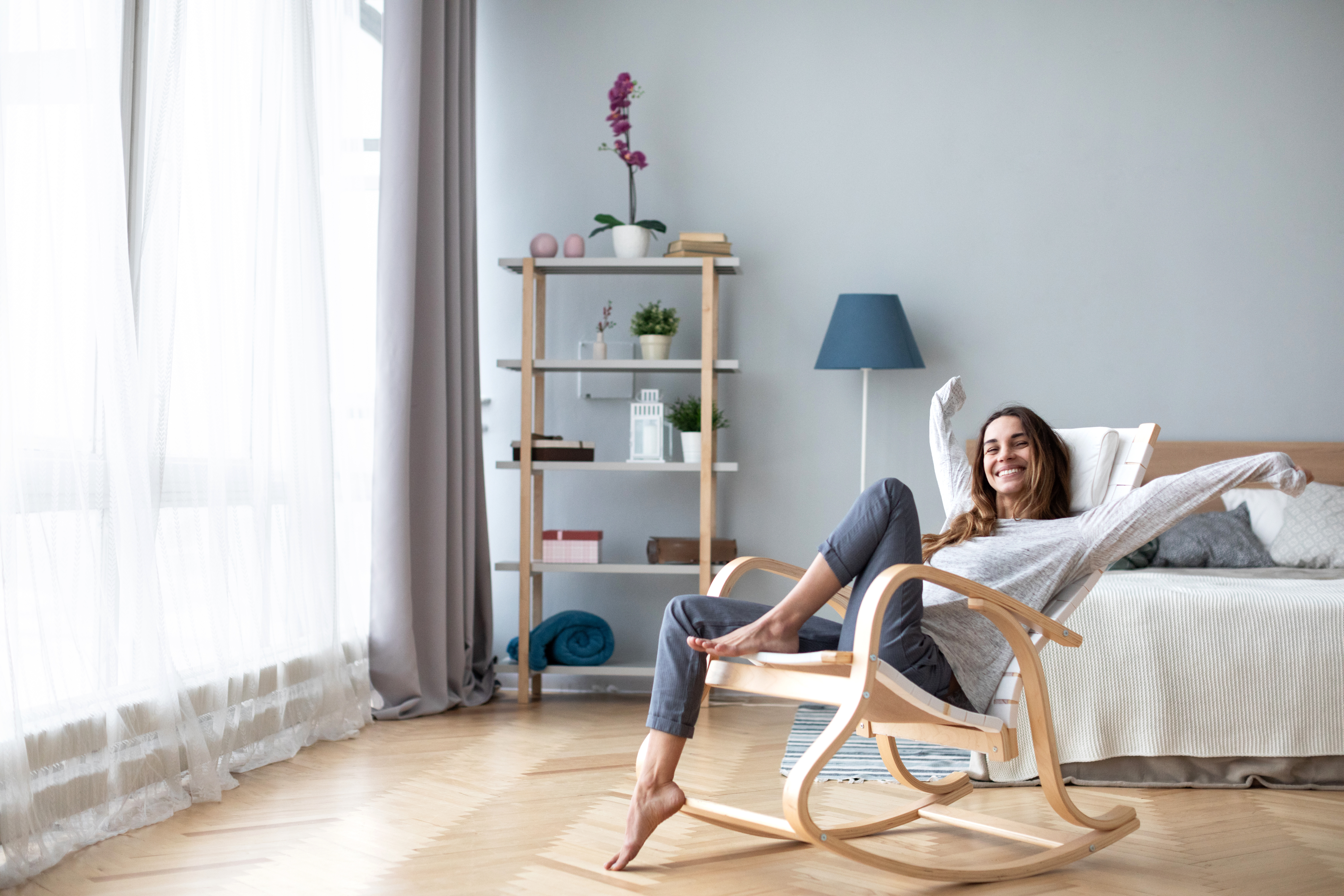 Happy woman resting comfortably sitting on modern chair in the living room at home