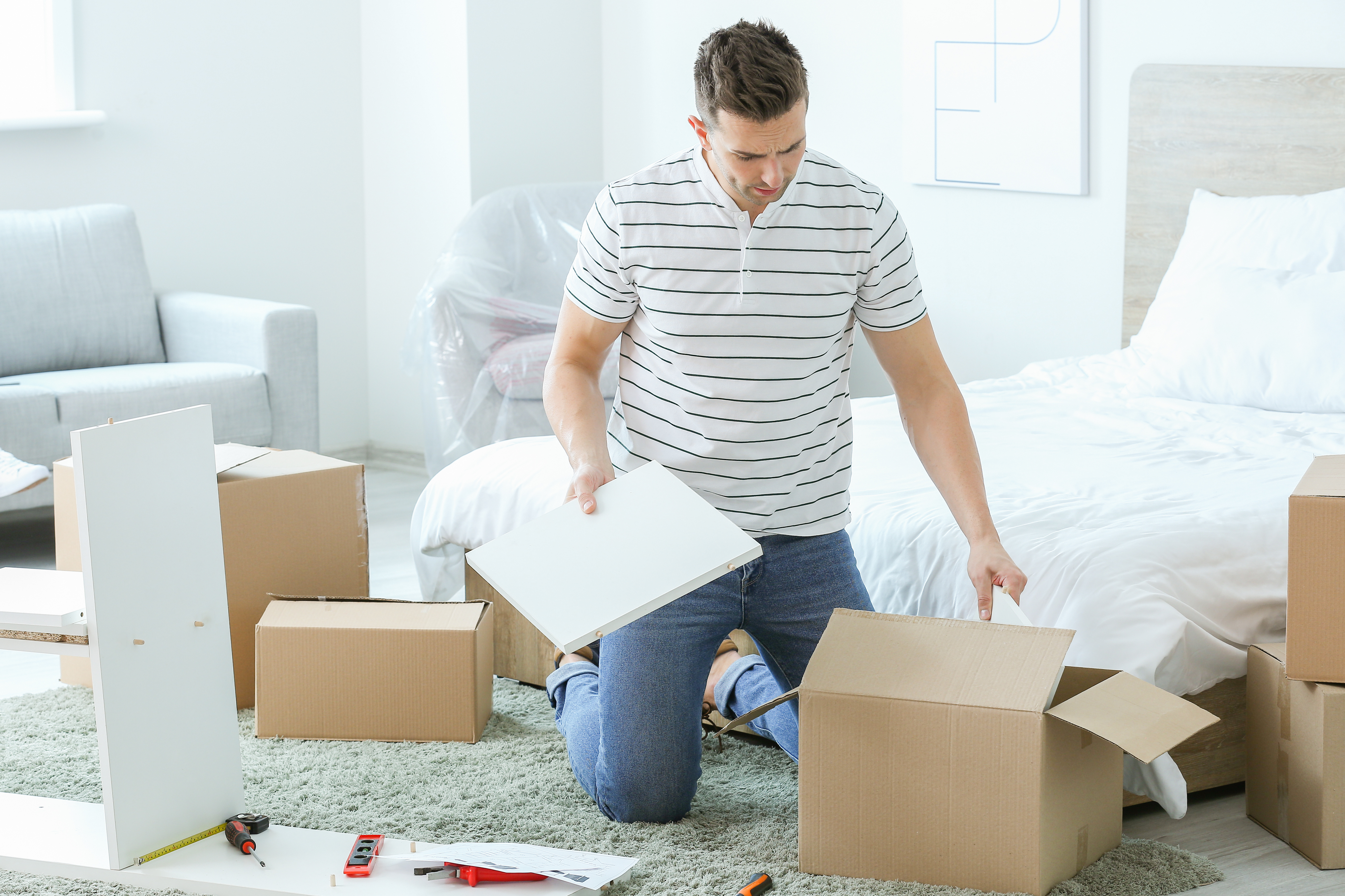 man unpacking boxes assembling new furniture