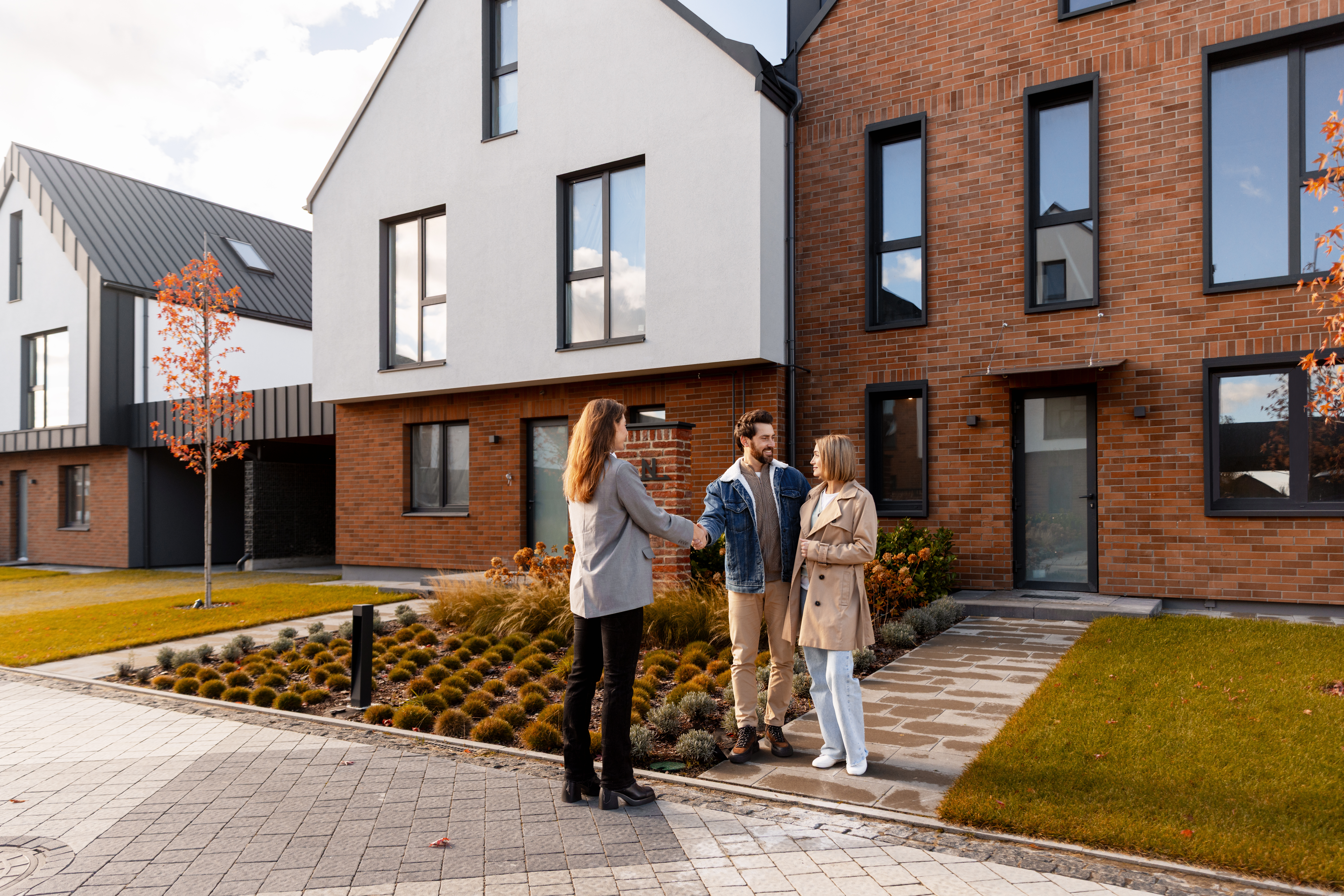 real_estate_agent_shaking_hands_with_happy_couple_buying_house