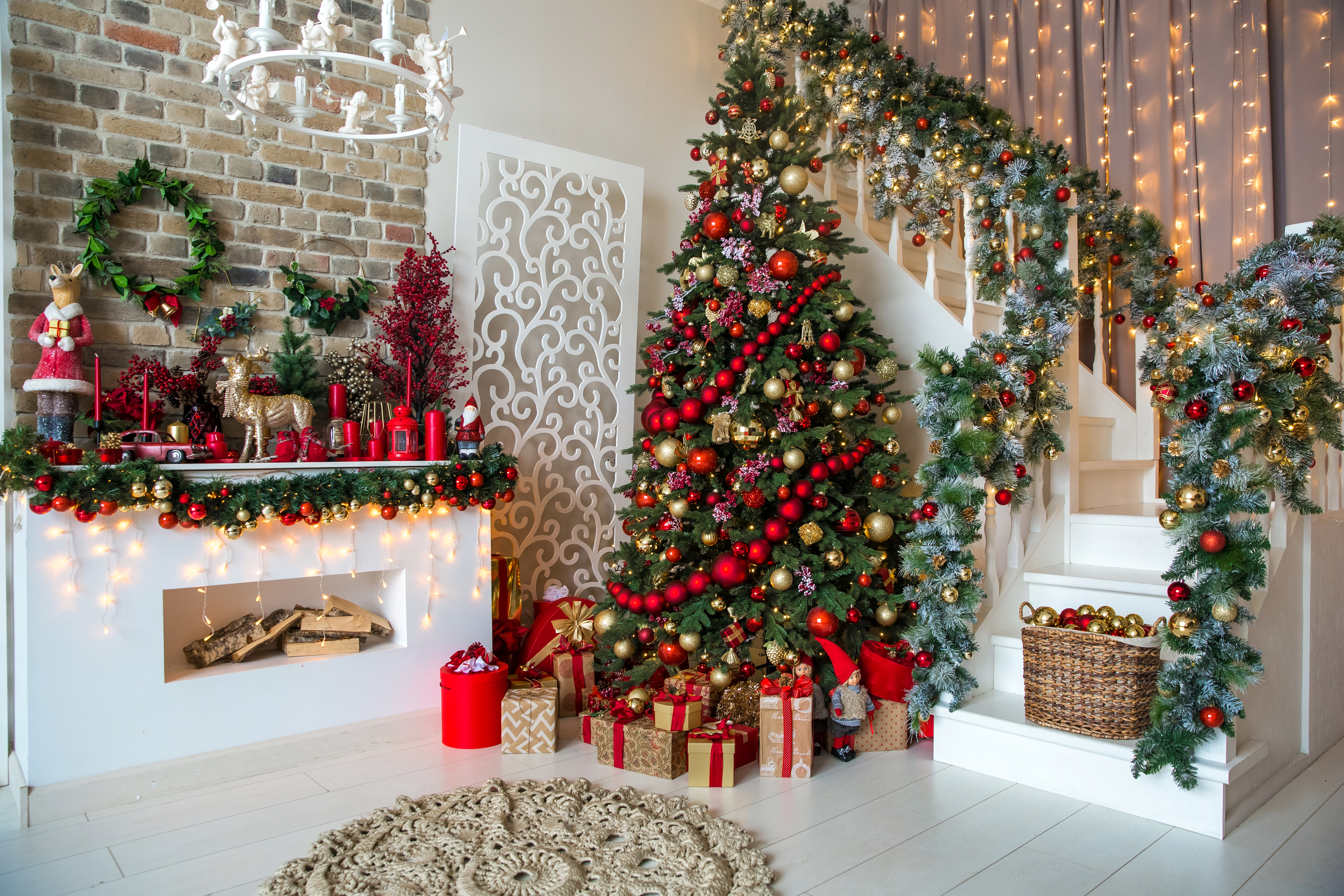 White room interior in red tones with New Year tree decorated, present boxes and artificial fireplace