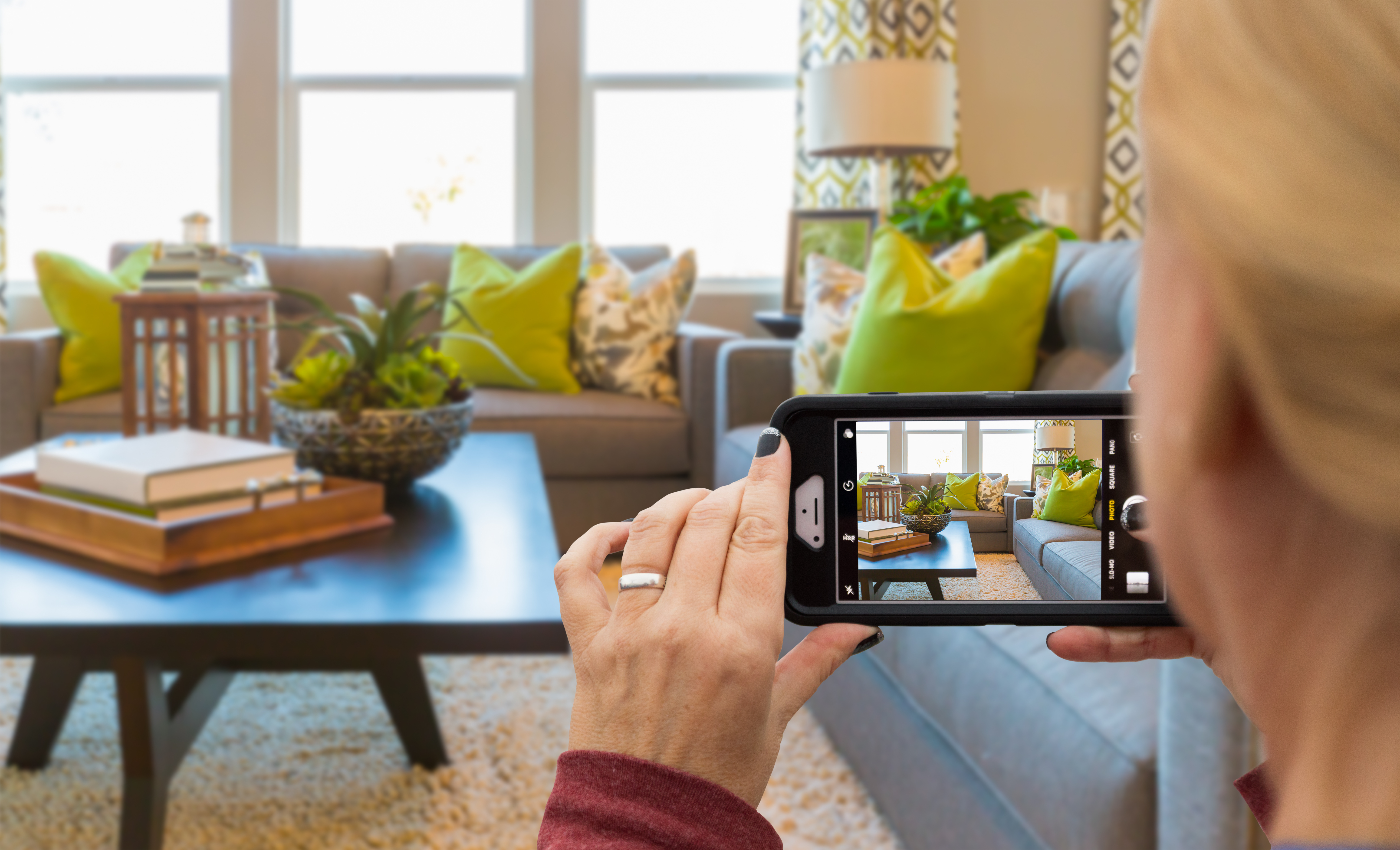 Woman Taking Pictures of A Living Room in Model Home with Her Smart Phone