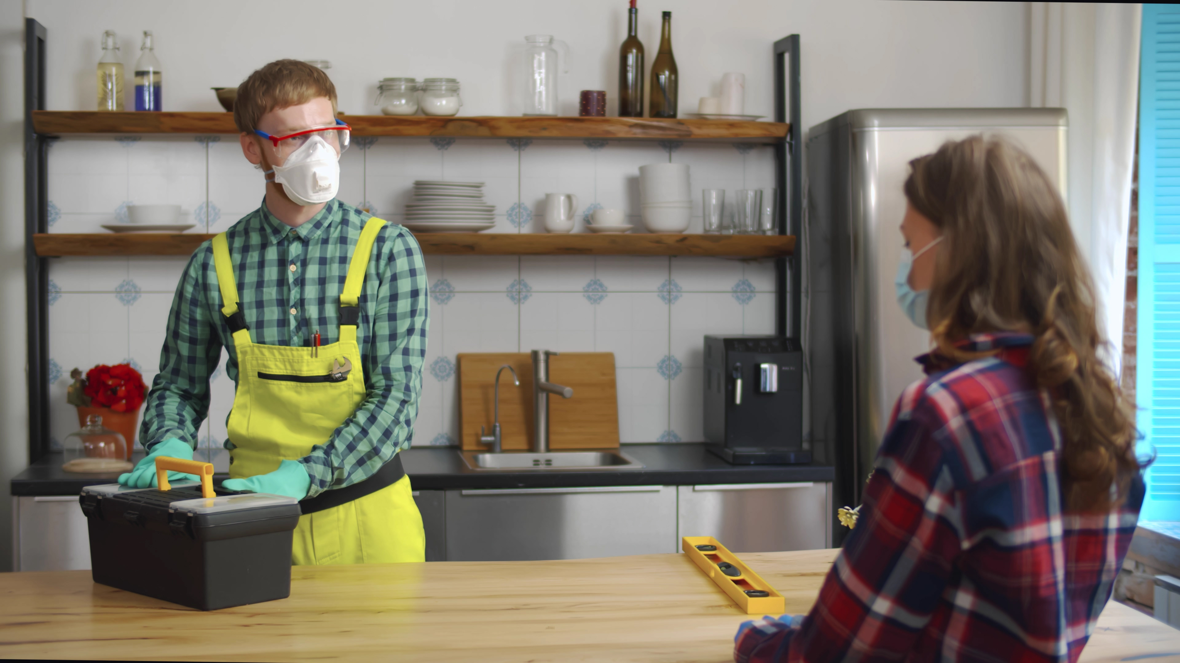 Woman welcome repairman at home wearing protective masks