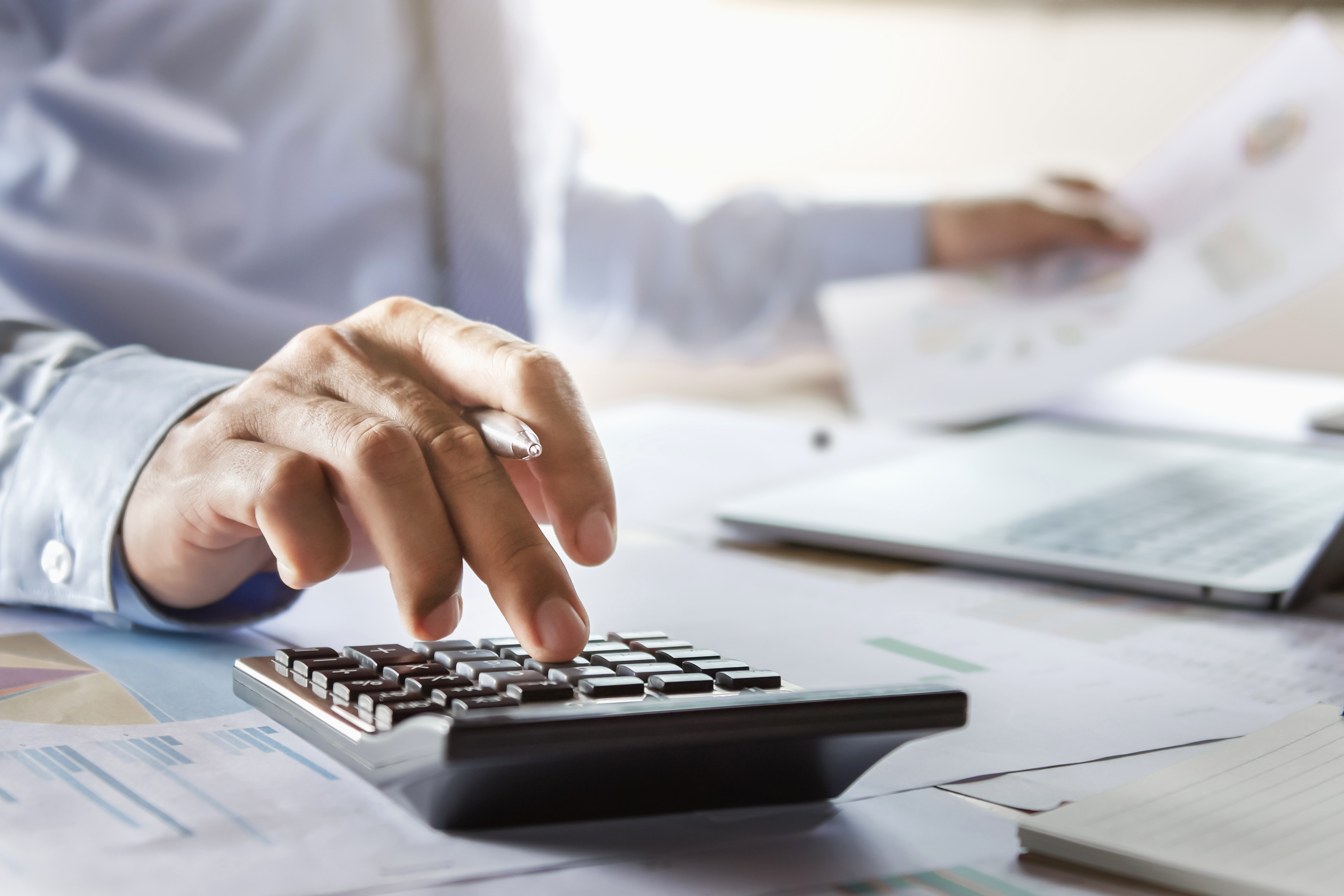 business man adding fees on calculator with documents