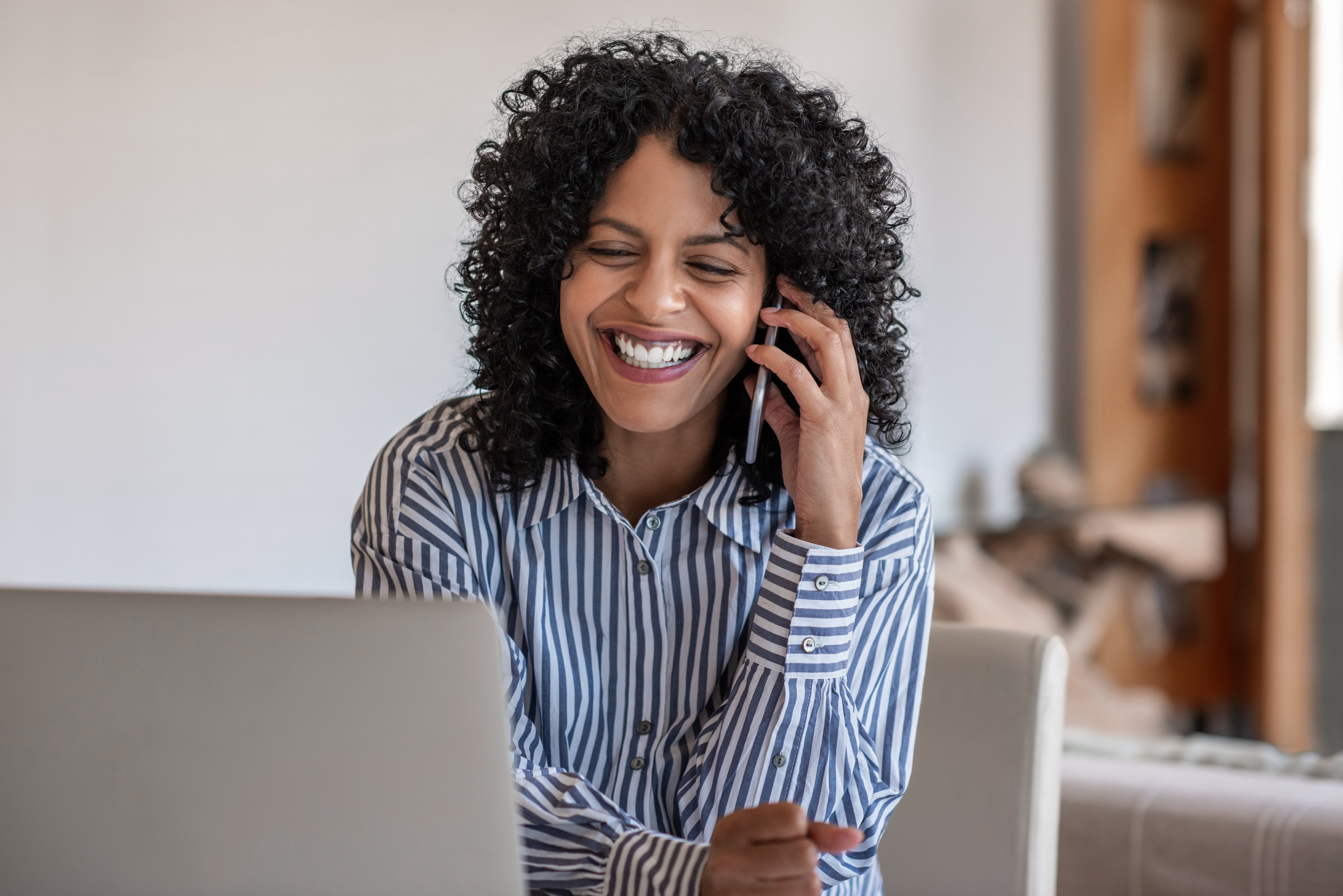 Laughing female entrepreneur talking with a client on her cellphone