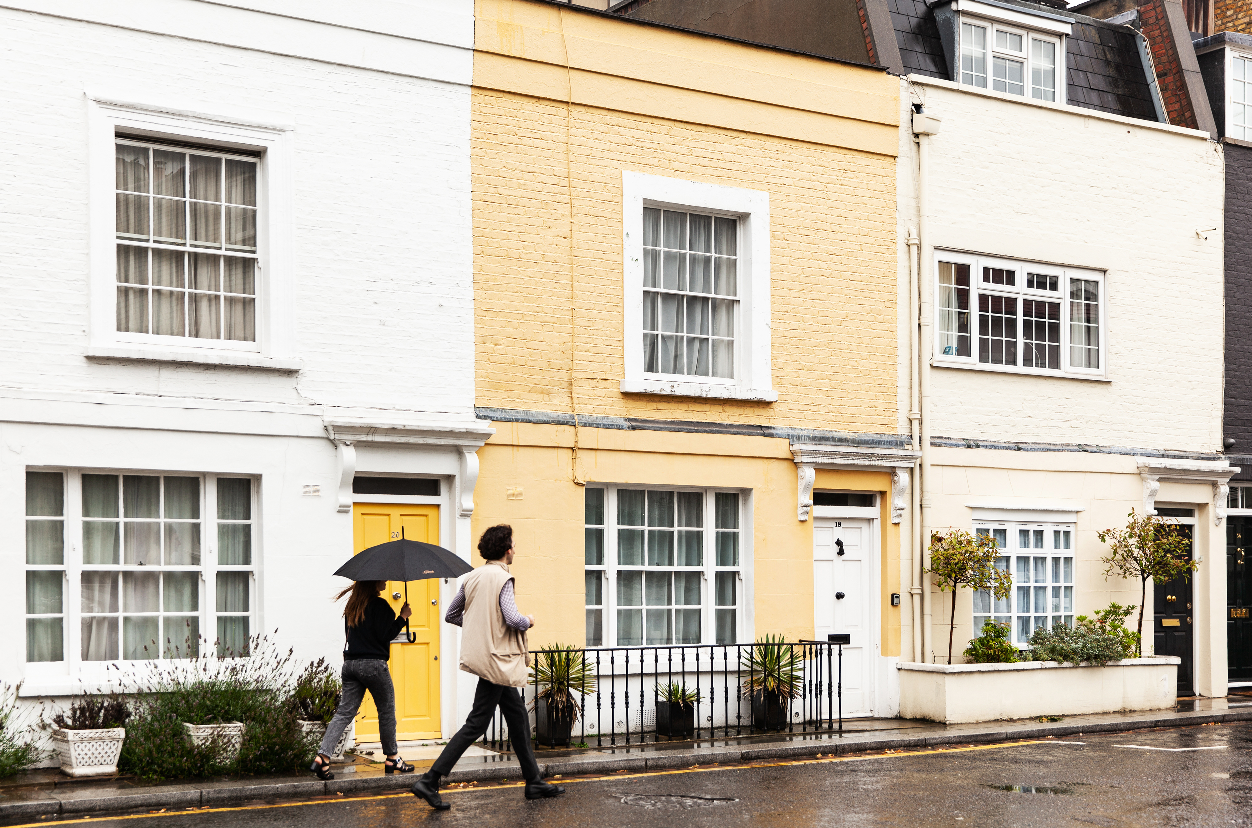 walking people on the street with colorful houses in the UK