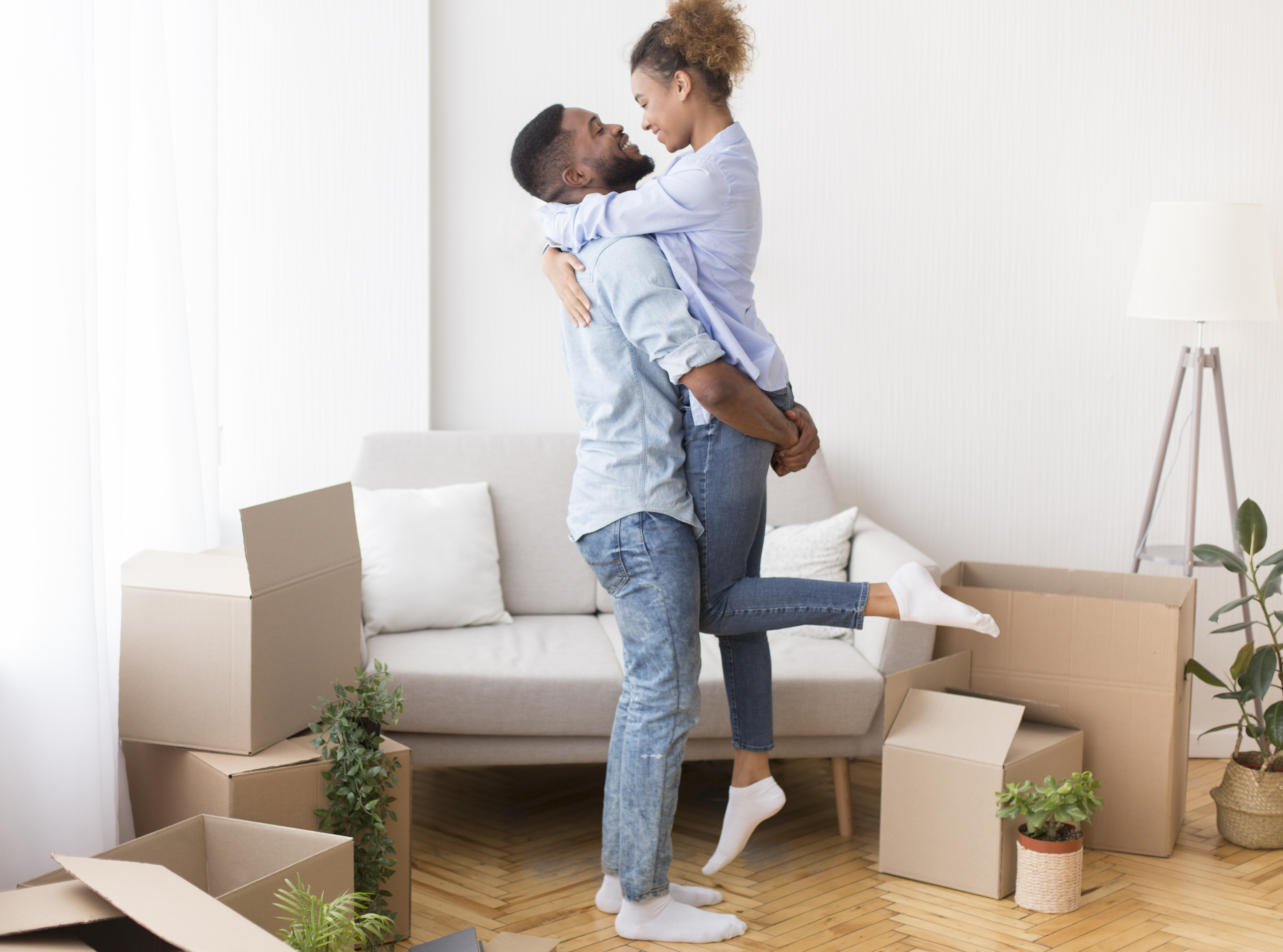 Boyfriend Lifting Girlfriend Among Moving Boxes In New House